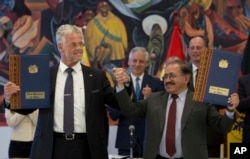 FILE - ACI Systems GmbH's President Wolfgang Schmutz from Germany, left, and manager of state company of Yacimientos Boliviano de Litio, Juan Carlos Montenegro, pose for photos during a signing ceremony in government palace in La Paz, Bolivia, Oct. 5, 2018.