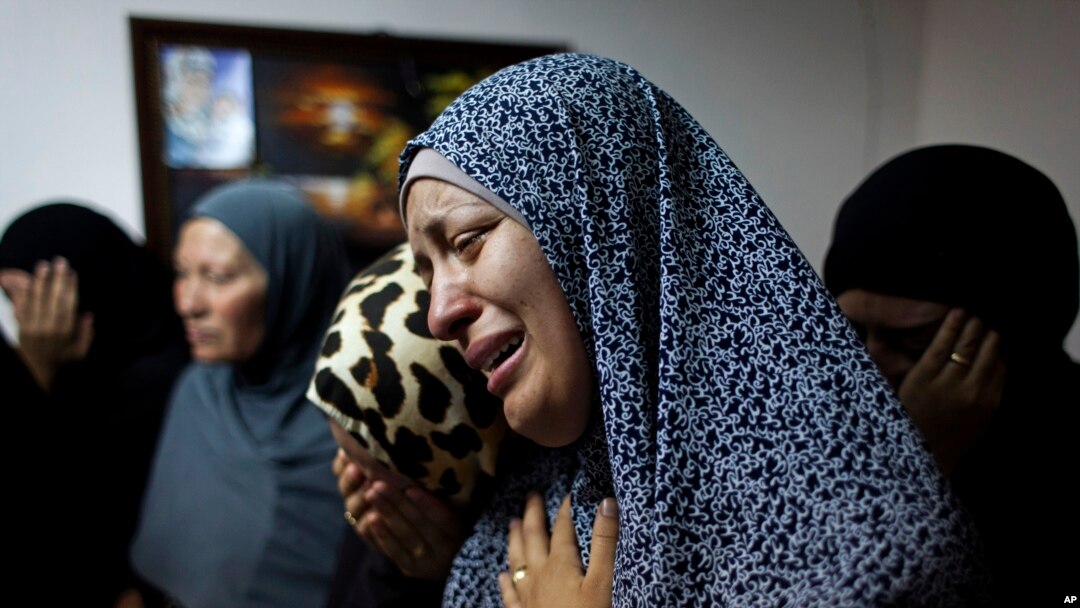Female relatives of slain Palestinian Ahmad Arafat Sabarin, 20, who was killed by Israeli army fire early Monday during a confrontation between stone throwers and Israeli soldiers, cries with a relative at the family house, prior to his funeral procession in the refugee camp of Jalazoun, on the outskirts of Ramallah, Monday, June 16, 2014.