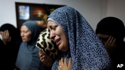 Female relatives of slain Palestinian Ahmad Arafat Sabarin, 20, who was killed by Israeli army fire early Monday during a confrontation between stone throwers and Israeli soldiers, cries with a relative at the family house, prior to his funeral procession in the refugee camp of Jalazoun, on the outskirts of Ramallah, Monday, June 16, 2014.