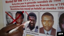 Jean Claude Ndatabaye, secrétaire administratif de l'Unité de suivi des fugitifs du génocide, barre la photo d'Augustin Bizimana, l'un des fugitifs les plus recherchés du génocide rwandais de 1994, à Kigali, au Rwanda le 22 mai 2020.