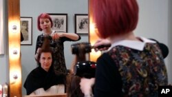 FILE - Lisa Meyer blow drys the hair of a client at her Hair and Beauty shop in London, May 16, 2018. 