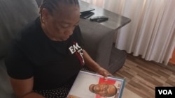 Torkwase Kuraun, Sister of missing journalist Tordue Salem, looks at pictures of him in the family photo album at her home in Abuja, Nov. 4, 2021. (Timothy. Obiezu/VOA)