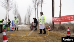 身穿防護服的中國警察和工人2019年2月26日在河北省通向一處發現非洲豬瘟的農場的檢查站進行消毒。