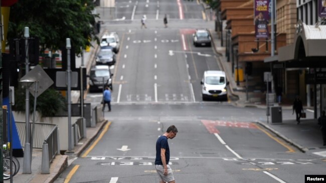 Seorang pria melintasi jalan pusat kota yang sebagian besar kosong ketika orang-orang di Greater Brisbane telah diperintahkan untuk dikunci ketika pihak berwenang mencoba untuk menekan klaster COVID-19 yang berkembang di Brisbane, Australia, 30 Maret 2021. (Foto: Reuters)