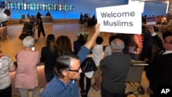 John Wider holds up a sign welcoming Muslims in the Tom Bradley International Terminal at Los Angeles International Airport, June 29, 2017.