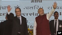 French President Francois Hollande, left, and Indian Prime Minister Narendra Modi wave at the audience as they arrive for the foundation stone laying for the headquarters of the International Solar Allliance at Gurgaon, outskirts of New Delhi, India, Jan.