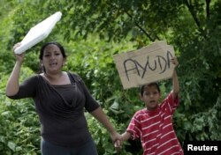 Local residents hold up a poster along a road near the village of Canoa, April 25, 2016, after an earthquake struck off Ecuador's Pacific coast. The sign reads "help."