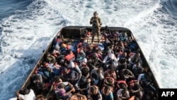 لیبیا کے کوسٹل گارڈز کا ایک اہل کار سمندر سے تارکین وطن کی کشتی پکڑ کر واپس لا رہا ہے جس پر 147 افراد سوار ہیں۔ 