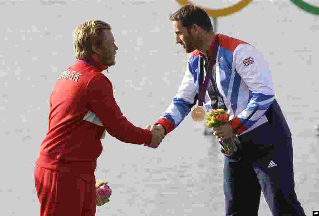 Ben Ainslie of Great Britain, right, winner of the gold medal, shakes hands with silver medallist Jonas Hogh-Christensen of Denmark after the Finn class sailing competition at the London 2012 Summer Olympics, August 5, 2012.