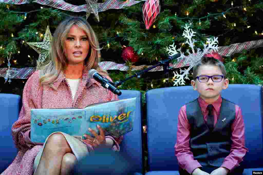 ABD First Lady&rsquo;si Melania Trump başkent Washington&rsquo;da Ulusal Çocuk Sağlığı Sistemi adlı kuruluşa yaptığı ziyaret sırasında çocuklara Noel hikayeleri okuyor. Yanında oturan çocuk Nathan Simm