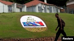 A man walks past a floral display announcing the 5th BRICS Summit in Durban, Mar. 25, 2013.