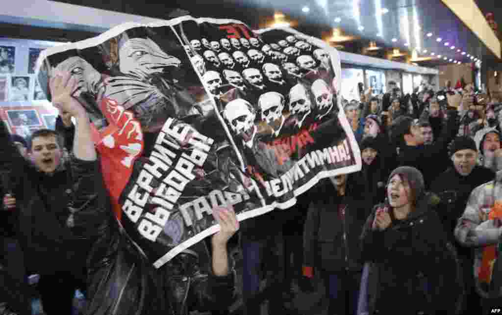 Opposition demonstrators hold a poster reading "Give back the elections, rascals" during protests against alleged vote rigging in Russia's parliamentary elections in Triumphal Square in Moscow, Russia, Tuesday, Dec. 6, 2011. Police clashed Tuesday on a c