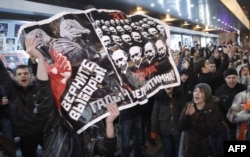 FILE - Opposition demonstrators hold a poster reading "Give back the elections, rascals" during protests against alleged vote rigging in Russia's parliamentary elections in Triumphal Square in Moscow, Russia, Dec. 6, 2011.