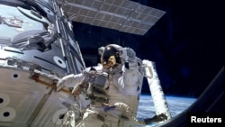 FILE - A U.S. astronaut waves during a spacewalk outside the International Space Station.