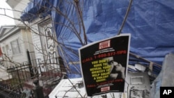 A crime stoppers poster hangs in front of debris outside a fire-damaged home near the Imam Al-Khoei Islamic Center in the Queens, New York, Jan. 2, 2012.
