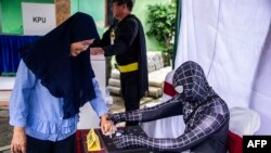 Para petugas pemilu mengenakan kostum superhero di sebuah TPS di Surabaya pada pemilu serentak hari Rabu (17/4).
