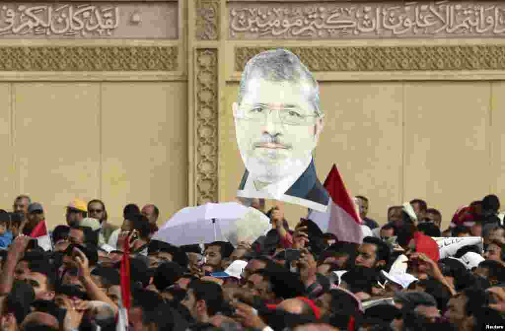 Supporters of Egyptian President Mohamed Morsi chant slogans and carry an image of Morsi, during a protest praising a new decree he issued on Thursday, in front of the presidential palace in Cairo, Egypt, November 23 , 2012.