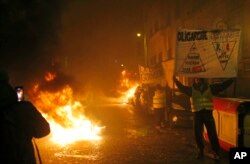 Demonstrators wearing yellow vests hold banners next to burning barricades near the Champs-Elysees during a yellow vest protest in Paris, Jan. 5, 2019.