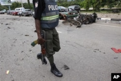 Militants from Nigeria's oil rich Niger Delta set off several small bombs in the capital during ceremonies marking the 50th anniversary. A Nigerian police officer walks past the burnt out shell of a car, after a car bomb exploded in Abuja, Nigeria.