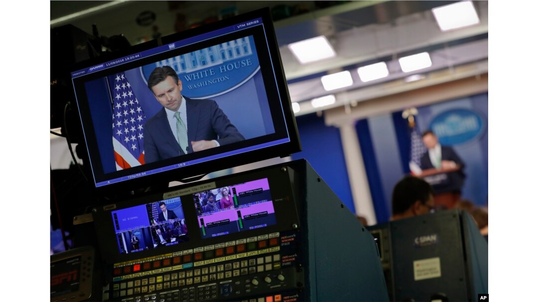 White House press secretary Josh Earnest is seen on broadcast television monitors as he begins to speak to the media during the daily briefing in the Brady Press Briefing Room of the White House, Nov. 9, 2016.