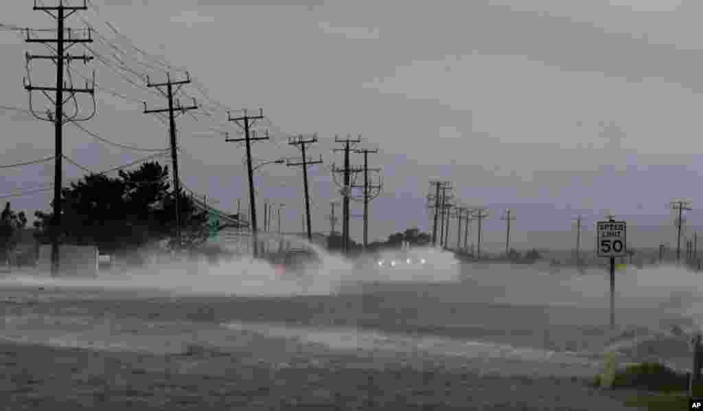 Vehicles navigate a flooded Highway 64 as wind pushes water over the road as Hurricane Arthur passes through Nags Head, North Carolina, July 4, 2014.