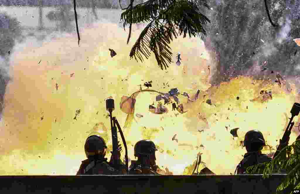 Members of the National Guard are caught up in a blast during protests in Caracas, Venezuela.