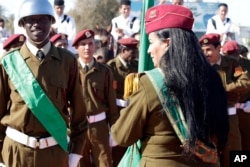 A female colonel in the Libyan Army holds the national flag as she waits with other soldiers for African leaders at Tripoli’s airport, Libya, Sunday, April 10, 2011. (AP/Pier Paolo Cito)