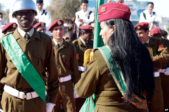 A female colonel in the Libyan Army holds the national flag as she waits with other soldiers for African leaders at Tripoli’s airport, Libya, Sunday, April 10, 2011. (AP/Pier Paolo Cito)