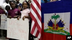 Children stand next to United States and Haitian flags as they hold signs in support of renewing TPS for immigrants from Central America and Haiti now living in the United States, during a news conference, Nov. 6, 2017, in Miami.
