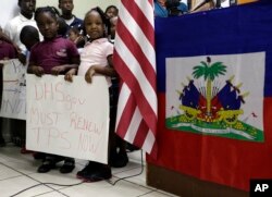 FILE - Children stand next to United States and Haitian flags as they hold signs in support of renewing Temporary Protected Status (TPS) for immigrants from Central America and Haiti now living in the United States, during a news conference in Miami, Nov. 6, 2017.