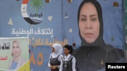 Girls walk past campaign posters of candidates ahead of parliamentary elections, in Tikrit, Iraq, April 29, 2018.