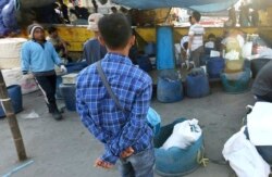 Sulistyo (kiri), nelayan Indonesia yang dipaksa bekerja di kapal penangkap ikan asing yang mengirim ikan untuk pemasok, Sea To Table, memperhatian nelayan memilah hasil tangkapan di pelabuhan nelayan, Jakarta, 31 Maret 2018.