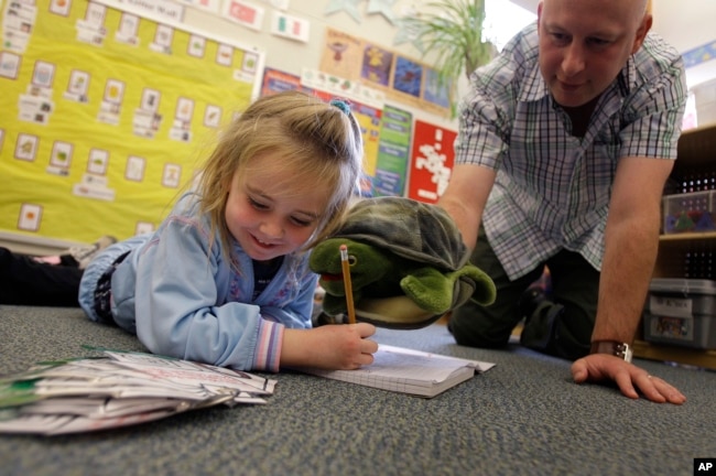 Teacher Matt Bugaj uses a Twiggle the Turtle hand puppet to teach a "Twiggle the Turtle" conflict resolution lesson to Kaylee Schaefer, 4, at Bennett Family Child Care Center in University Park, Pa., Friday, Nov. 14, 2008. (AP Photo/Carolyn Kaster)