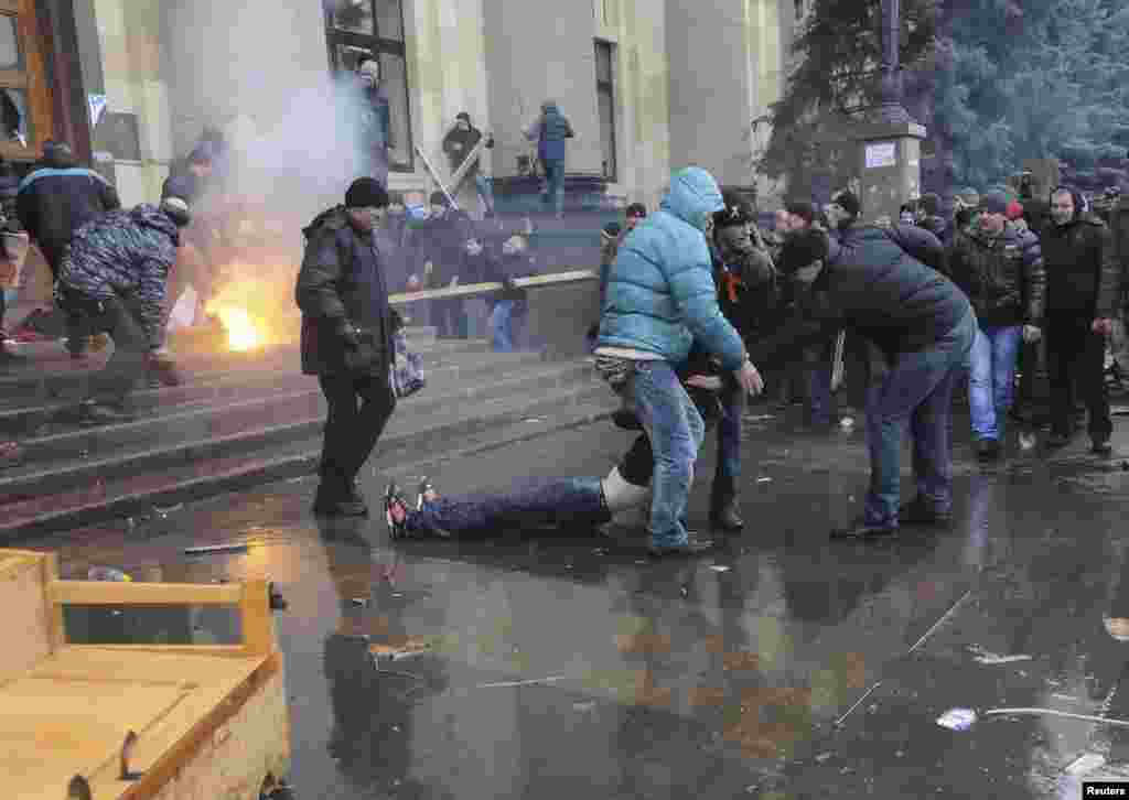 In central Kharkiv, pro-Russian protesters drag a wounded man during clashes with supporters of Ukraine&#39;s new government as pro-Russia activists tried to seize the regional governor&#39;s headquarters, Interfax news agency said.