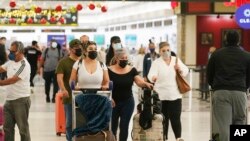 Travelers walk through Miami International Airport, Dec. 20, 2021, in Miami. 