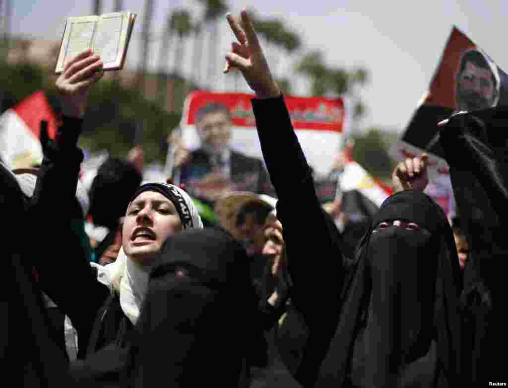 A protester, who supports former Egyptian President Mohamed Morsi, holds up a copy of the Koran as she and others march near Cairo University after Friday prayers in Cairo, July 5, 2013.