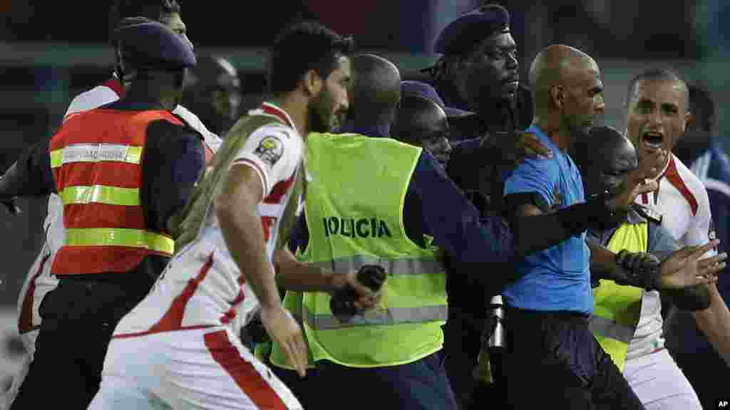 O juíz Rajindraparsad Seechum, de azul, é protegido por seguranças contra os jogadores da Tunísia na final do jogo contra a Guiné Equatorial.