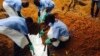 Volunteers lower a corpse, which is prepared with safe burial practices to ensure it does not pose a health risk to others and stop the chain of person-to-person transmission of Ebola, into a grave in Kailahun, Sierra Leone, July 18, 2014.