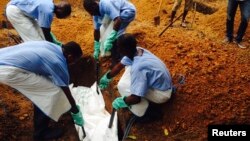 Volunteers lower a corpse, which is prepared with safe burial practices to ensure it does not pose a health risk to others and stop the chain of person-to-person transmission of Ebola, into a grave in Kailahun, Sierra Leone, July 18, 2014.