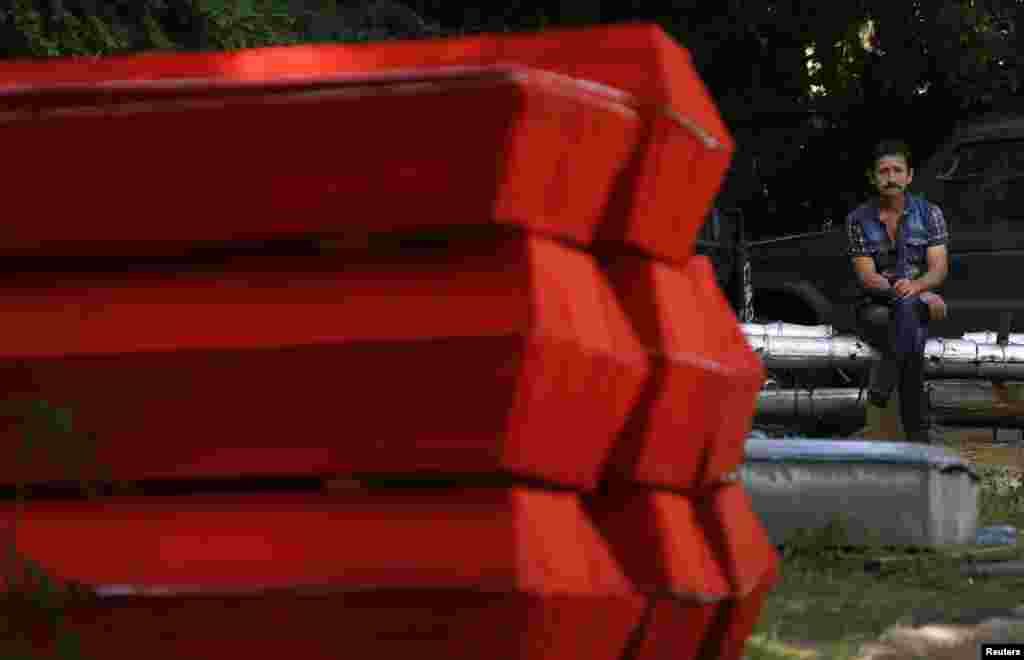 A man sits by thirty coffins prepared for the funerals of pro-Russian rebels killed during heavy fighting at Donetsk airport on May 26, outside a Donetsk morgue, Ukraine, May 29, 2014. 