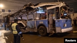 A policeman watches as a bus, destroyed in an earlier explosion, is towed away in Volgograd on December 30, 2013. 