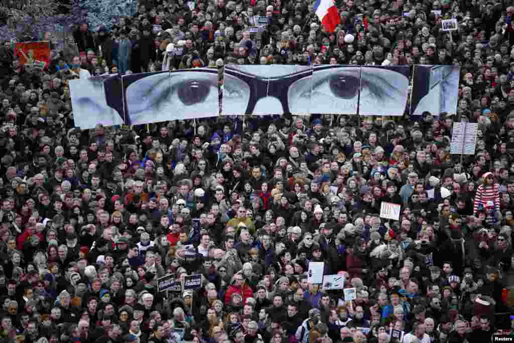 Người tuần hành cầm các tấm bảng tạo thành đôi mắt của cố biên tập viên Stephane Charbonnier của báo Charlie Hebdo, trong cuộc tuần hành bày tỏ tinh thần đoàn kết trong thủ đô Paris.