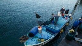 In this May 2, 2020 photo, fishermen work in their boat in the bay of San Cristobal, Galapagos Islands, Ecuador. Locals like to joke that, 