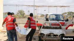 Des membres du Croissant-Rouge libyen transportent des cadavres d'un site où se déroulent des affrontements entre les forces pro-gouvernementales et le groupe islamiste Ansar al-Sharia à Benghazi, le 21 octobre 2014.