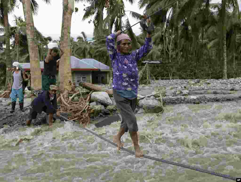 Residents cross a river using suspended ropes at Andap, New Bataan township, Compostela Valley in southern Philippines, December 5, 2012, a day after Typhoon Bopha made landfall.