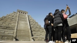 Students take pictures of themselves in front of a mock pyramid during the countdown to when many believe the Mayan people predicted the end of the world, Friday, Dec. 21, 2012, in Taichung, southern Taiwan.