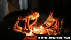 The government has cut power and water to Sur, in Diyarbakir, Turkey, as efforts are made to rebuild it. A family reads by the light of candles inside their home.