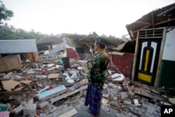 Seorang pria memeriksa reruntuhan rumahnya yang hancur akibat gempa di Lombok Utara, 9 Agustus 2018. (Foto: AP)