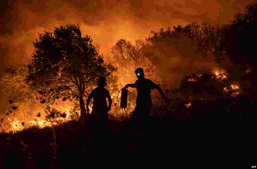 People try to extinguish a wildfire spreading in the village of Akcayaka in the area of Milas in the Mugla province, Turkey.