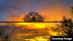 The sun sets over the gateway of peyotera Amada Cardenas's house in Mirando City, Texas. Ironwork reflects core Native American Church values of faith, hope, love and charity.